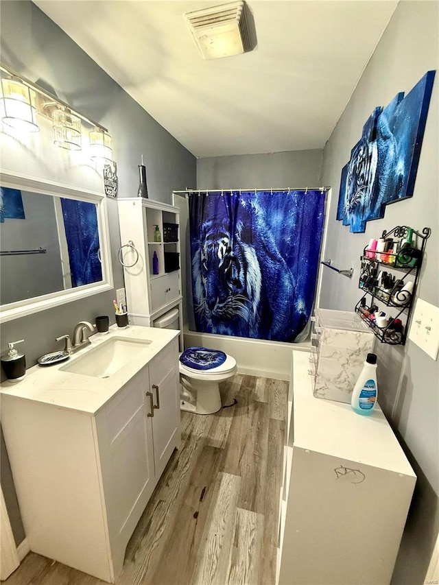 full bathroom featuring vanity, hardwood / wood-style flooring, shower / bath combination with curtain, and toilet