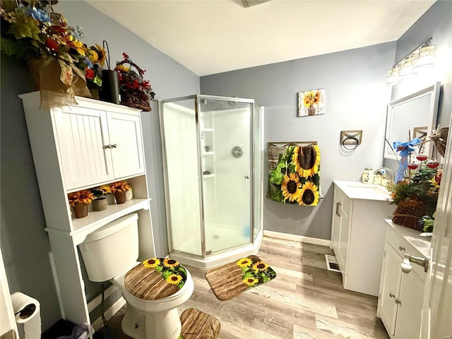 bathroom featuring hardwood / wood-style flooring, vanity, a shower with door, and toilet