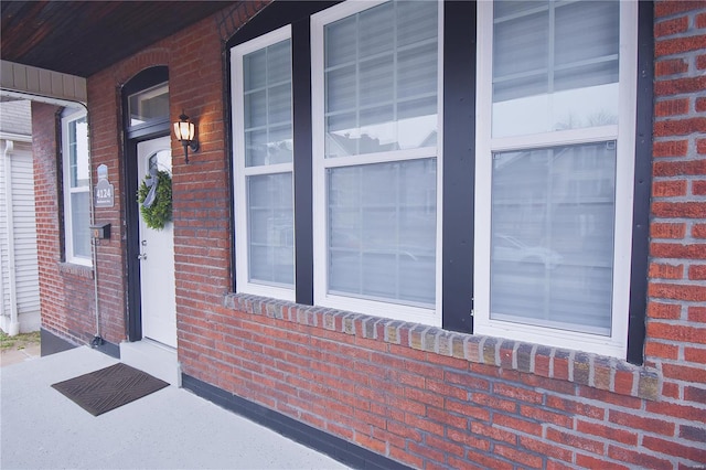 entrance to property featuring covered porch and brick siding