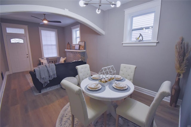 dining room featuring arched walkways, plenty of natural light, and dark wood finished floors