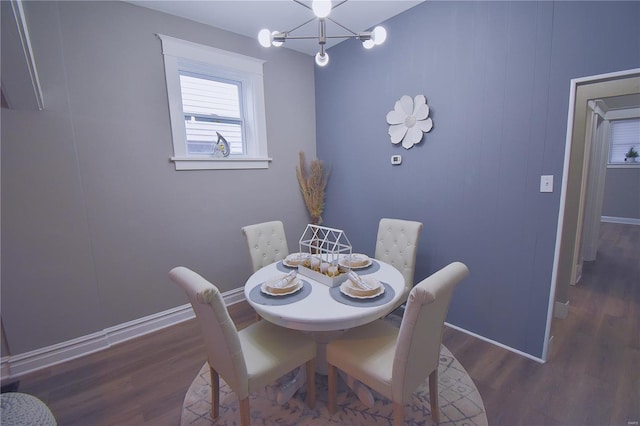 dining space featuring baseboards, a chandelier, and dark wood-style flooring