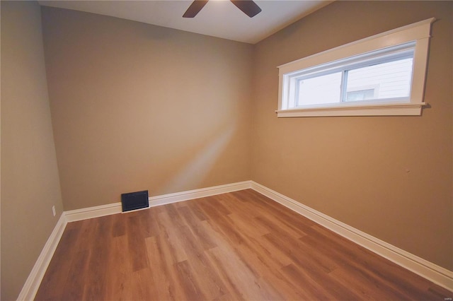 unfurnished room featuring a ceiling fan, wood finished floors, visible vents, and baseboards