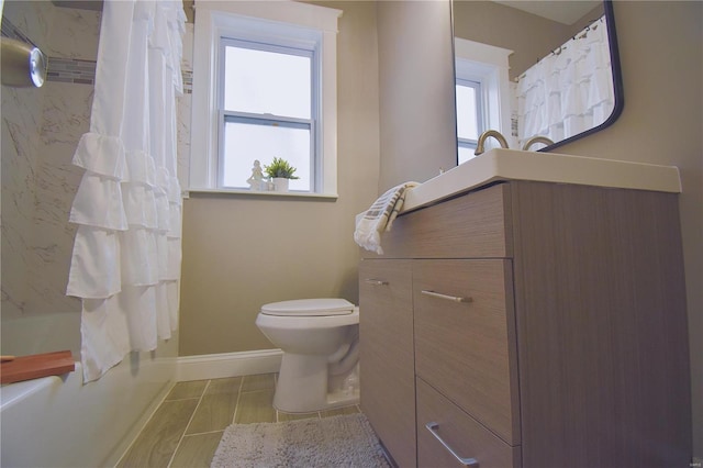 bathroom featuring shower / tub combo, plenty of natural light, toilet, and baseboards