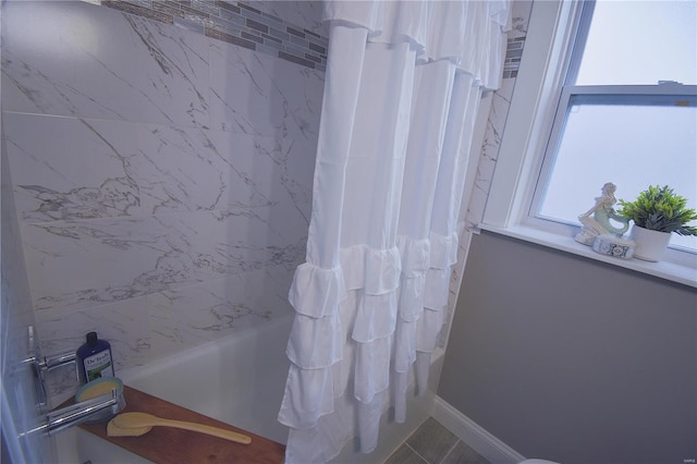 bathroom featuring baseboards and shower / bathtub combination with curtain