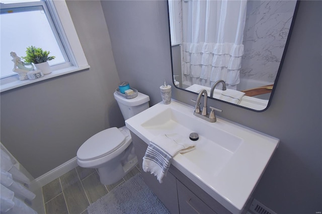 bathroom with toilet, baseboards, and vanity