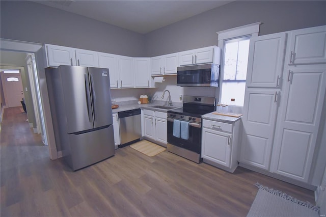 kitchen with stainless steel appliances, light countertops, white cabinets, and a sink