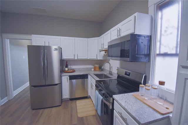 kitchen with stainless steel appliances, a wealth of natural light, white cabinetry, and a sink