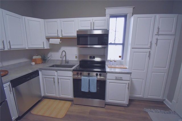 kitchen with dark wood-style flooring, light countertops, appliances with stainless steel finishes, white cabinets, and a sink