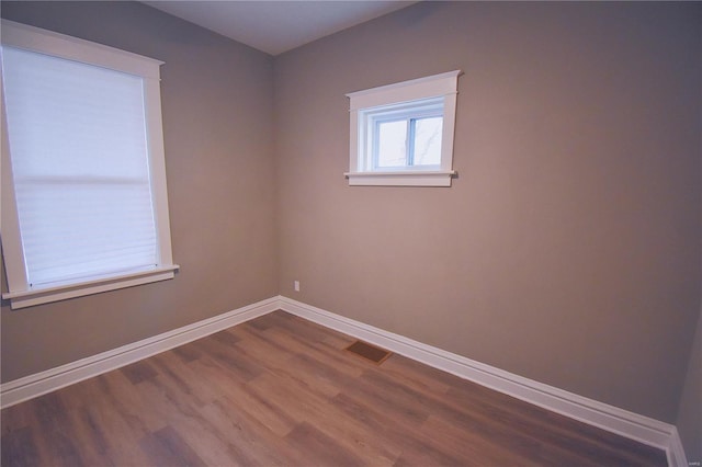 unfurnished room featuring visible vents, baseboards, and wood finished floors