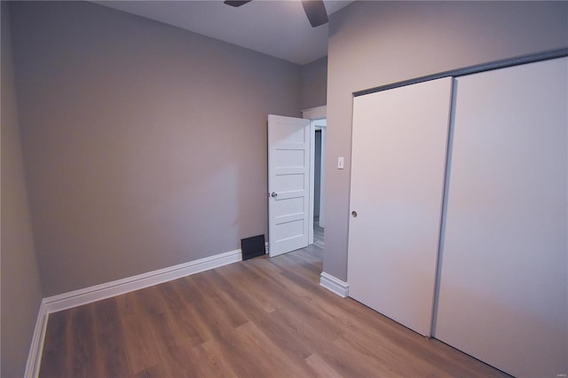 unfurnished bedroom featuring a ceiling fan, a closet, light wood-style flooring, and baseboards