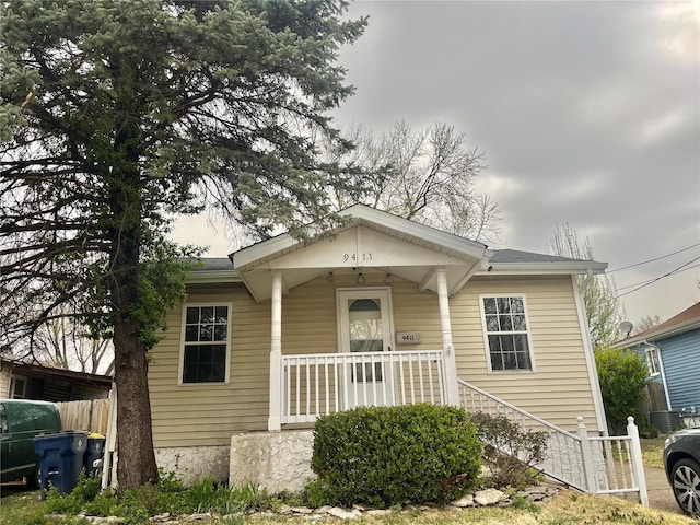 bungalow-style house with covered porch, central AC unit, and fence