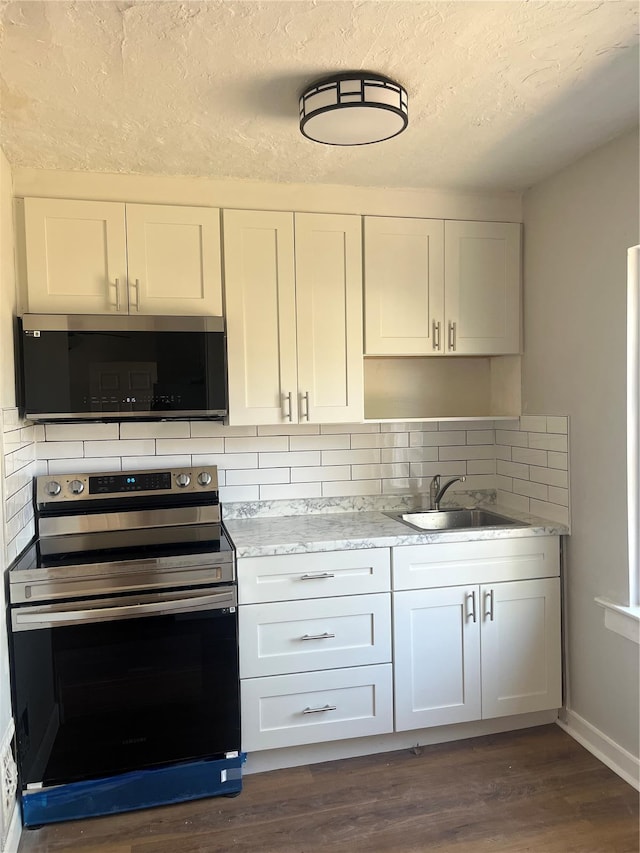kitchen featuring white cabinetry, tasteful backsplash, a sink, and stainless steel electric range oven