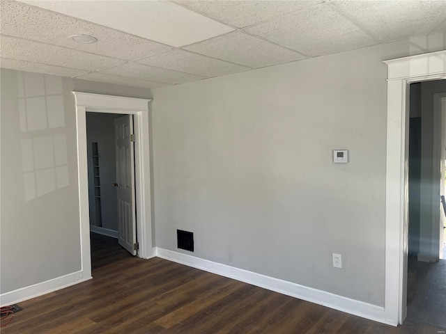 unfurnished room with dark wood-style floors, baseboards, and a paneled ceiling