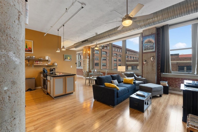 living room with rail lighting, light wood-style flooring, brick wall, and ceiling fan