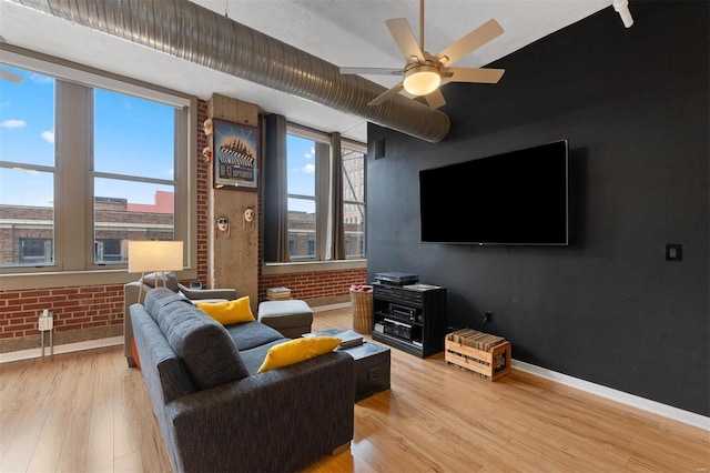 living room featuring brick wall, light wood finished floors, and a healthy amount of sunlight