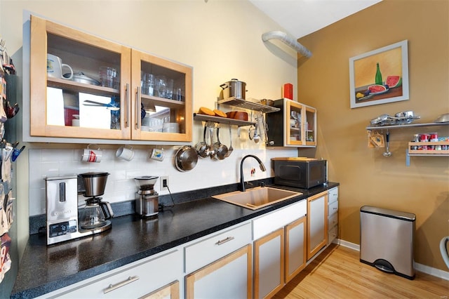 kitchen featuring black microwave, dark countertops, a sink, and decorative backsplash