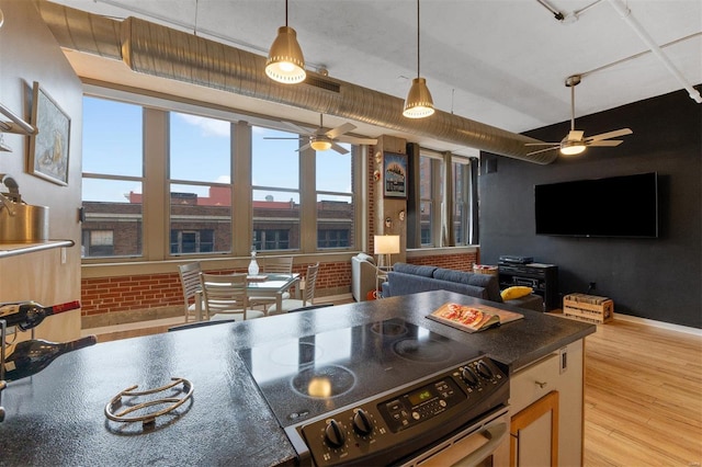 kitchen with dark countertops, open floor plan, stainless steel electric range, a healthy amount of sunlight, and light wood-style floors