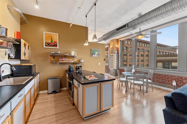 kitchen featuring glass insert cabinets, dark countertops, pendant lighting, and a sink