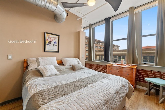 bedroom featuring multiple windows, light wood-style flooring, and baseboards