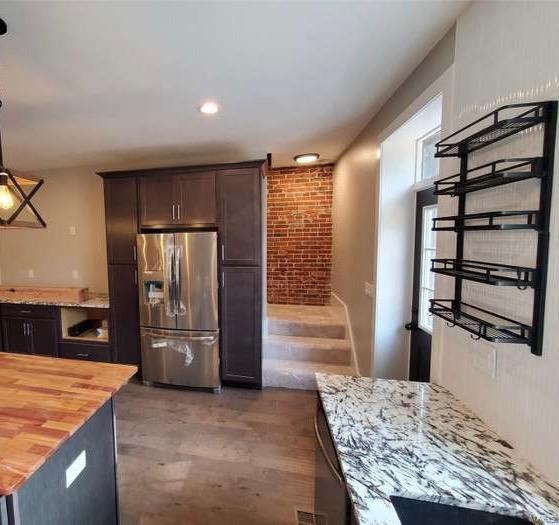 kitchen featuring decorative light fixtures, stainless steel refrigerator with ice dispenser, wooden counters, dark brown cabinetry, and plenty of natural light