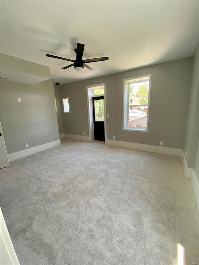 spare room featuring light carpet, baseboards, and a ceiling fan