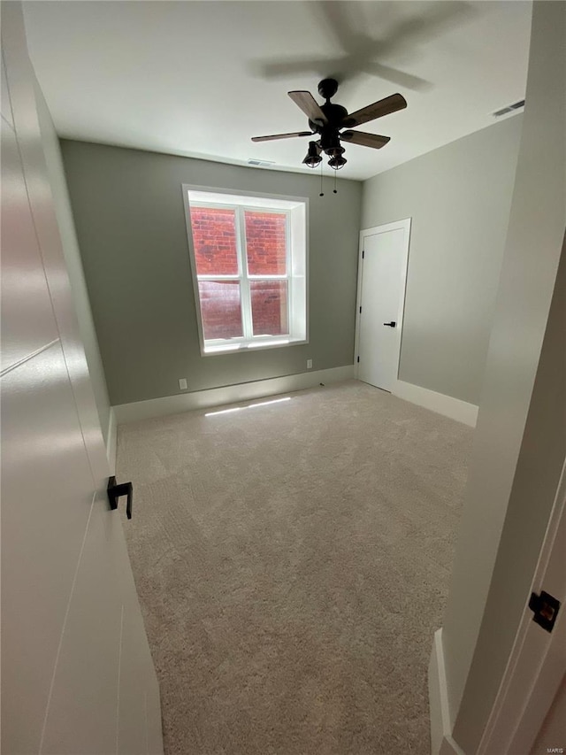 unfurnished room with visible vents, baseboards, ceiling fan, and light colored carpet