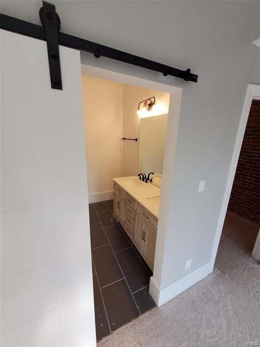 full bath with double vanity, a sink, and baseboards