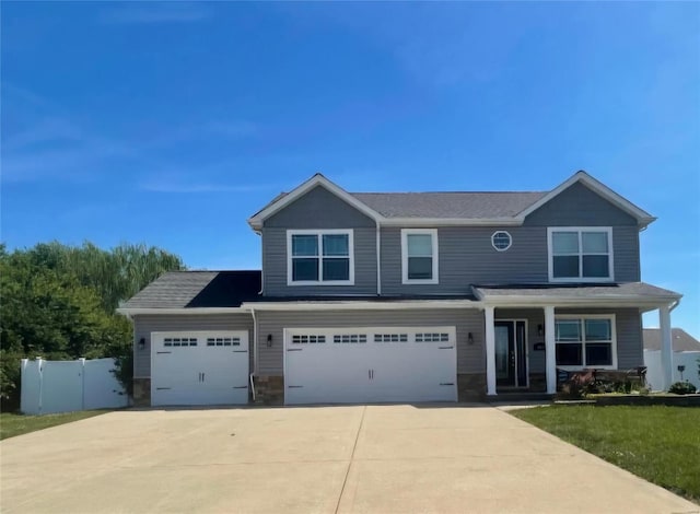 craftsman inspired home featuring an attached garage, covered porch, fence, and concrete driveway