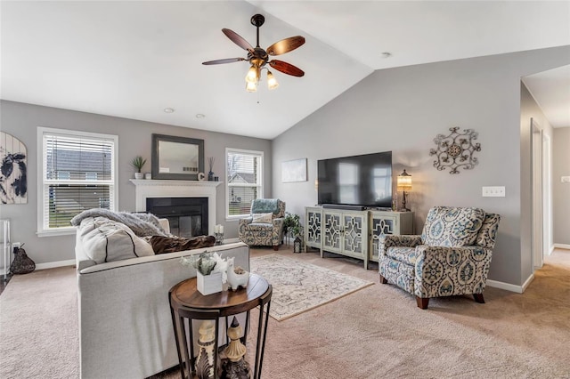 living room with a ceiling fan, baseboards, lofted ceiling, a glass covered fireplace, and carpet flooring