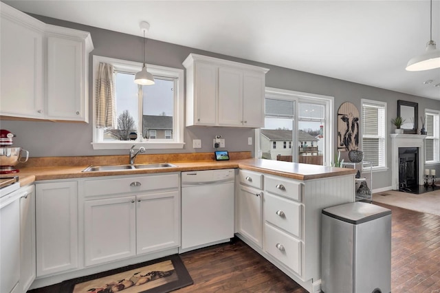 kitchen with a sink, a peninsula, white cabinets, and white dishwasher