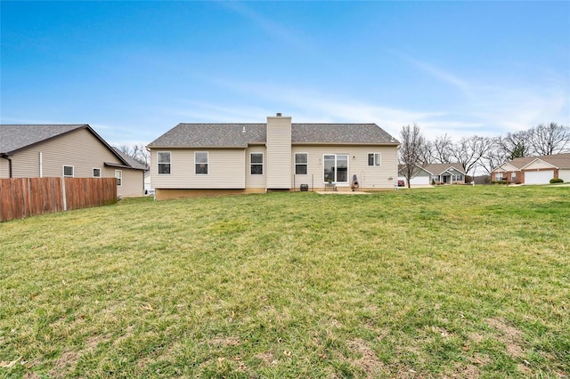 back of house featuring a lawn, a chimney, and fence