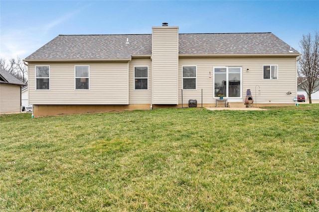 back of property featuring a shingled roof, a patio, a lawn, and a chimney