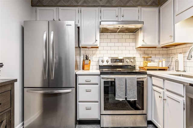 kitchen with stainless steel appliances, light countertops, decorative backsplash, a sink, and under cabinet range hood