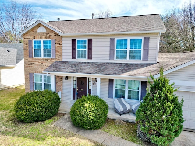 traditional-style house featuring a garage, brick siding, and roof with shingles