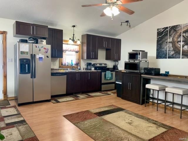 kitchen with vaulted ceiling, dark brown cabinets, appliances with stainless steel finishes, light hardwood / wood-style floors, and ceiling fan with notable chandelier