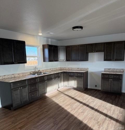 kitchen with dark hardwood / wood-style flooring, sink, and dark brown cabinetry