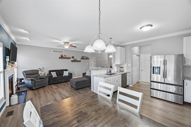 kitchen featuring open floor plan, stainless steel appliances, hanging light fixtures, and white cabinets