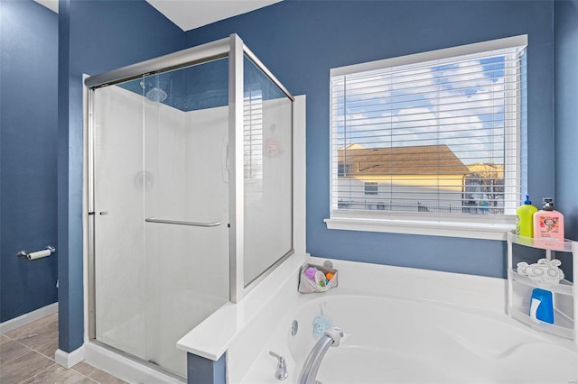 bathroom with a shower stall, baseboards, and a bath