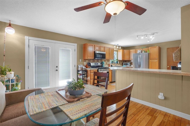 dining room with light wood-style floors, french doors, a toaster, and a textured ceiling