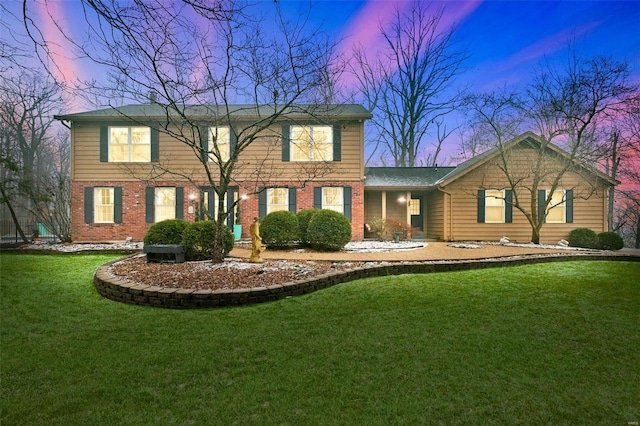 colonial home featuring brick siding and a lawn