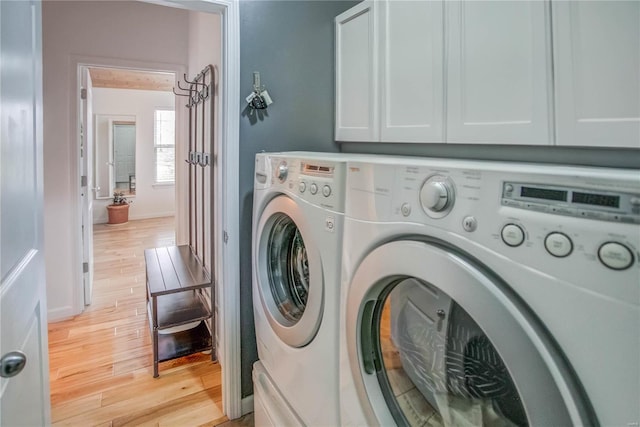 laundry room with cabinets, light hardwood / wood-style flooring, and washer and clothes dryer