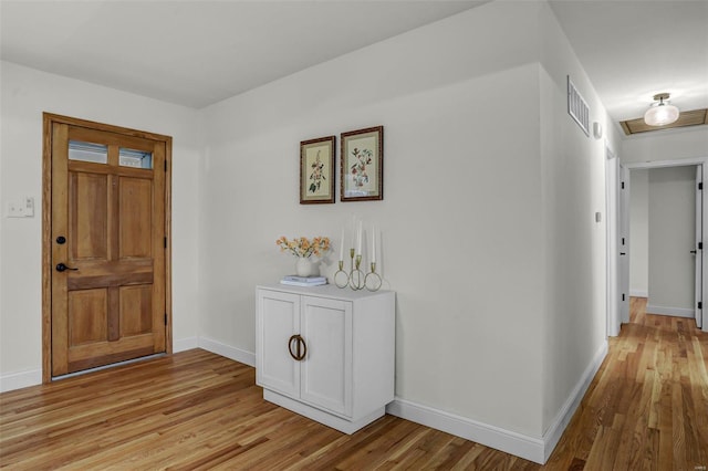 foyer entrance with visible vents, light wood-style flooring, and baseboards