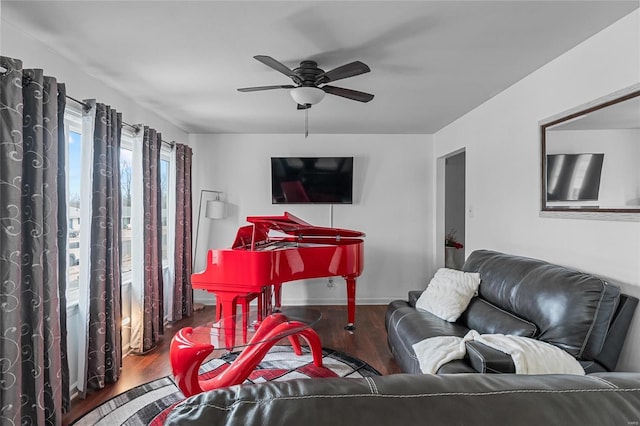 living area featuring a ceiling fan, baseboards, and wood finished floors