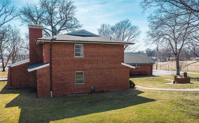 view of side of home with a lawn, brick siding, and a chimney