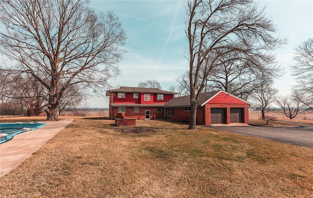 view of front of house with brick siding, aphalt driveway, an attached garage, and a front lawn