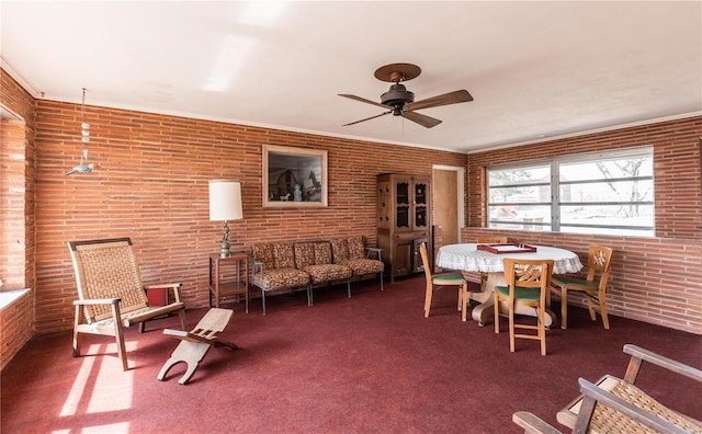 dining room featuring carpet floors, brick wall, and a ceiling fan