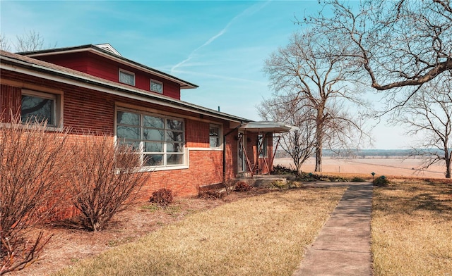 view of property exterior featuring brick siding and a lawn