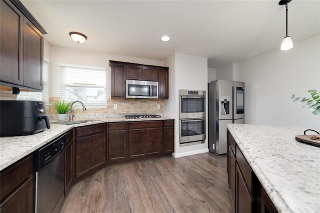 kitchen featuring dark hardwood / wood-style flooring, sink, tasteful backsplash, appliances with stainless steel finishes, and pendant lighting