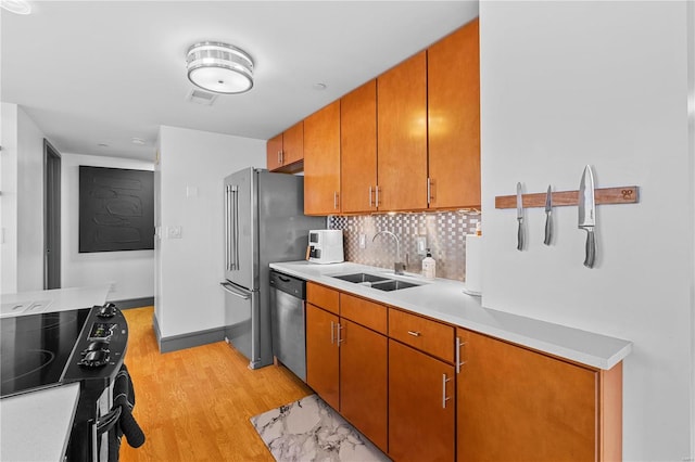 kitchen with electric stove, sink, dishwasher, light hardwood / wood-style floors, and tasteful backsplash