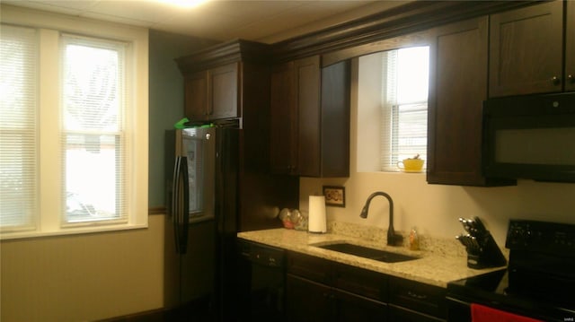 kitchen featuring dark brown cabinetry, sink, black appliances, and light stone countertops